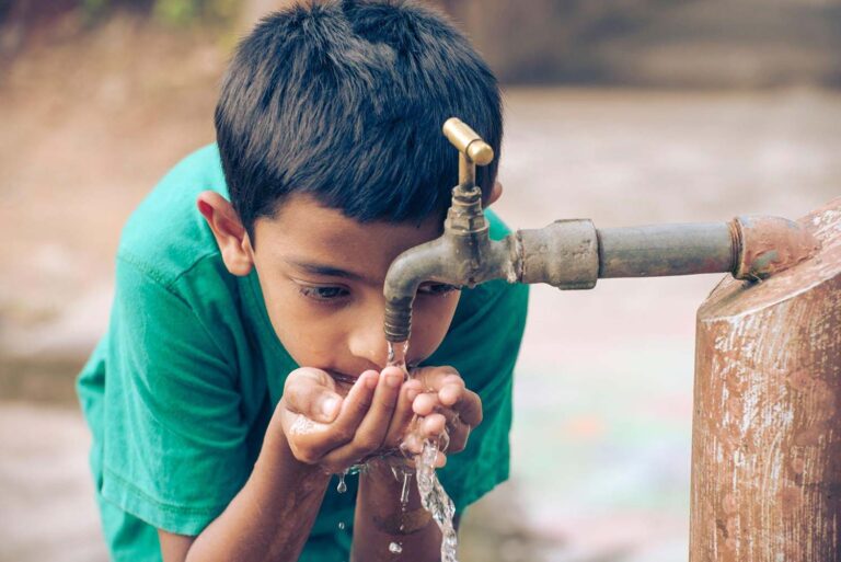 How-to-reduce-your-environmental-impact-at-home-Indian-boy-drinking-tap-water-outside